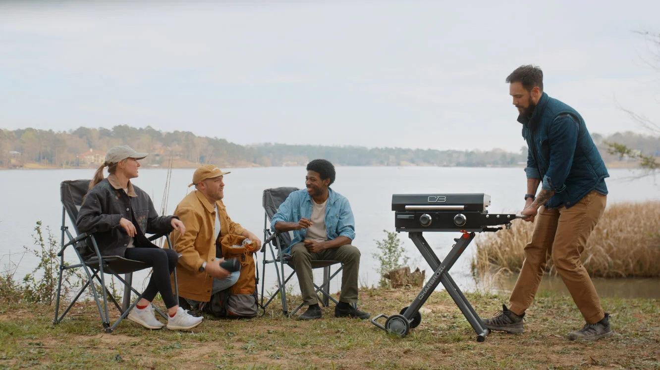 Four people around grill on lakeshore